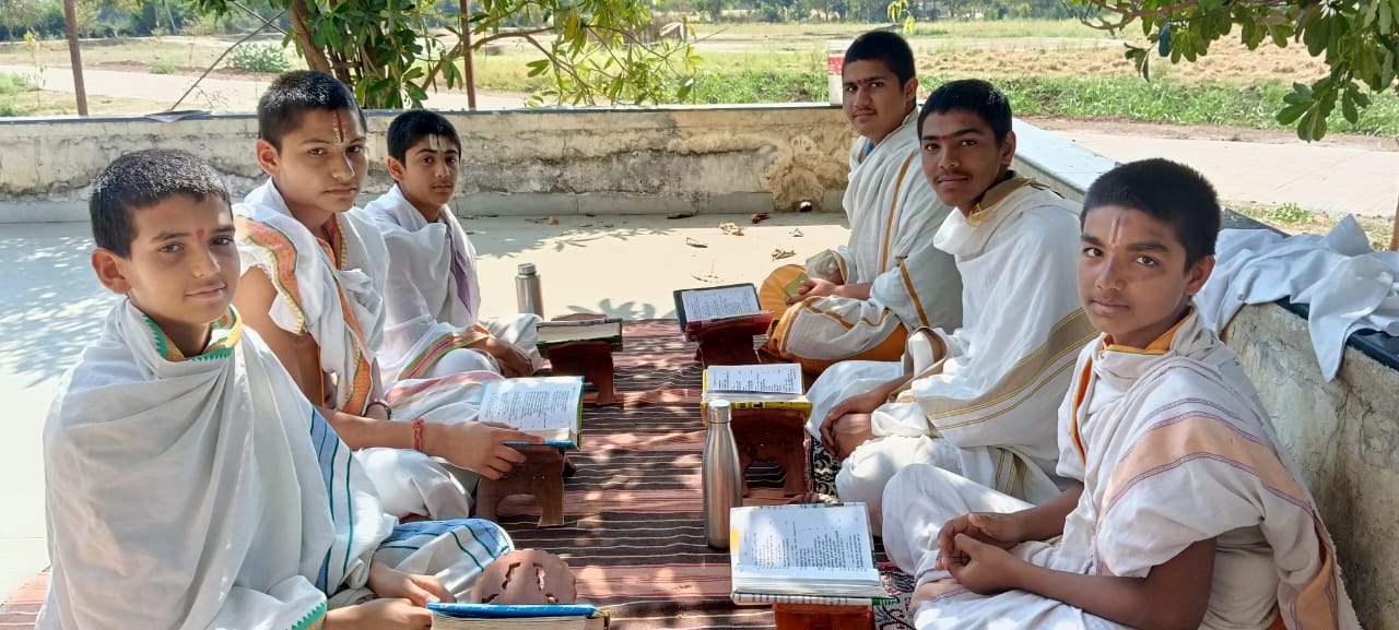 Gurukul students reading Sanskrit scriptures with their acharya